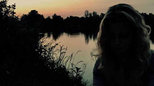 Close-up of silhouette tree against lake during sunset