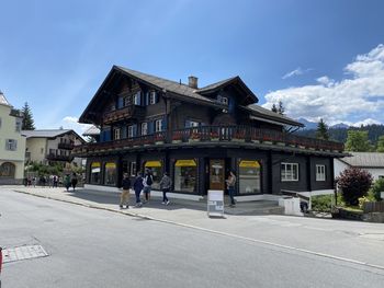 People walking on road by buildings against sky