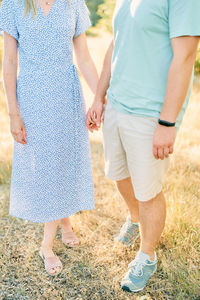 Low section of couple standing on field