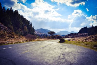 Empty road by mountains against sky