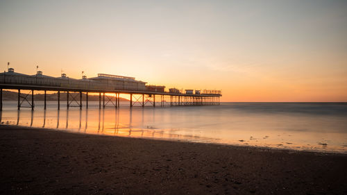 Pier over sea against sky during sunset