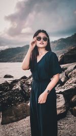 Young woman wearing sunglasses and standing on the beach