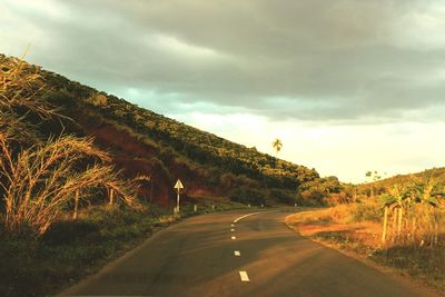 Country road against cloudy sky