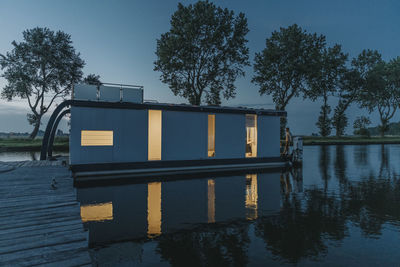 Man standing on illuminated houseboat at sunset