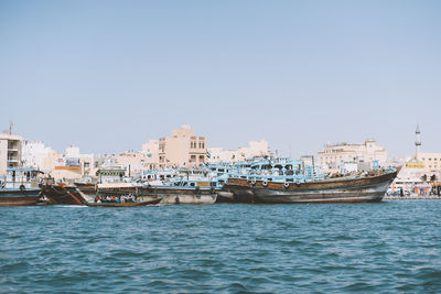 Sailboats in city against clear sky