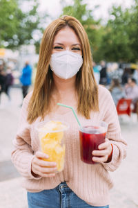 Woman with chips and cocktail during covid-19. female drinking with surgical mask person