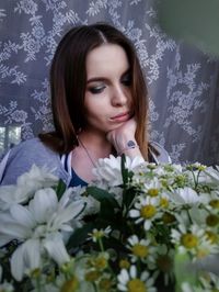 Portrait of beautiful woman against white flowering plants