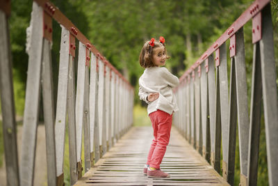 Portrait of cute girl looking over shoulder standing on footbridge