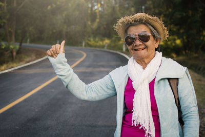 Woman hitchhiking while standing on road