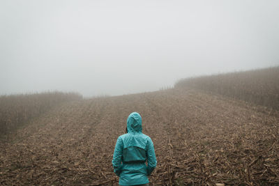 Rear view of man on field against sky during winter