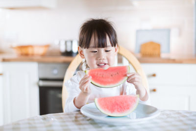 Young girl eating watermelon against real kitchen background