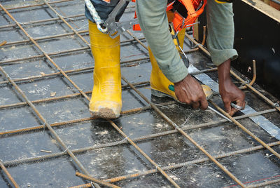 Low section of man working on metal fence