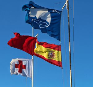 Low angle view of flag flags against clear blue sky