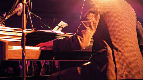 Midsection of man playing piano during music concert