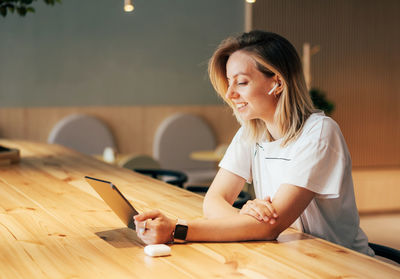 Young woman holding smart phone while sitting on table