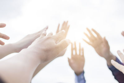 Low angle view of friends with arms raised against sky