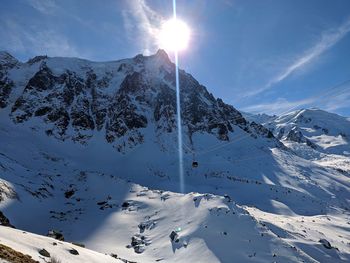 Scenic view of snow covered mountains against bright sun