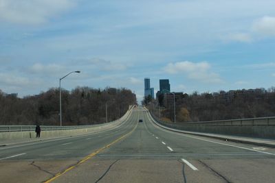 Road leading towards city against sky