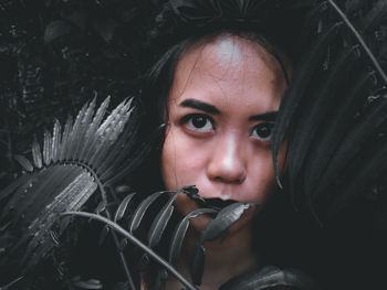 Portrait of young woman looking through leaves