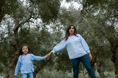 Mother and daughter holding hands while walking in park