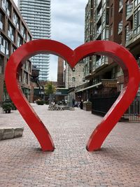 Red footpath amidst buildings in city