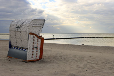 Hooded chairs on beach against sky