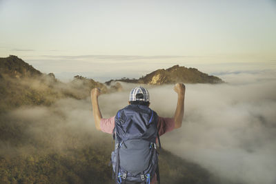 Young man with backpack enjoying sunset on peak mountain. tourist traveler.