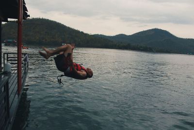 Side view of man in lake against sky