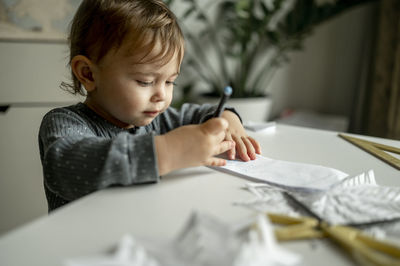 Toddler with colored pencil drawing on paper at home