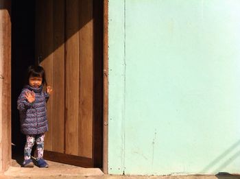 Girl standing at door and waving hand