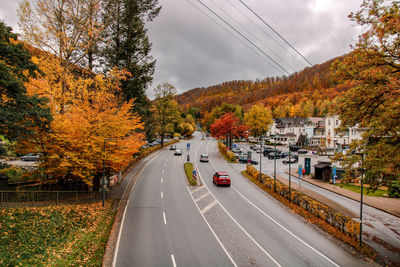 Road by trees against sky during autumn