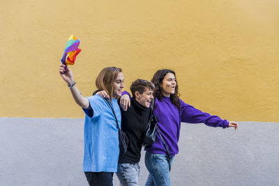 Young diverse friends walking on the street with pride rainbow flag.