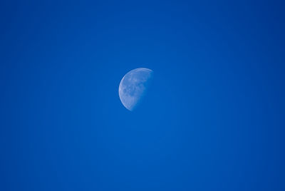 Low angle view of moon against blue sky