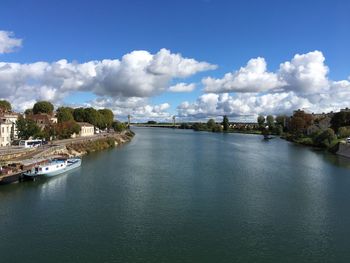 Scenic view of river by buildings against sky