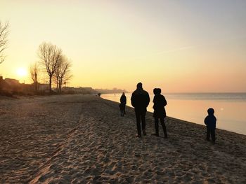 Silhouette people on beach against clear sky during sunset