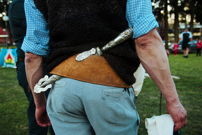 Midsection of man with dagger standing in park
