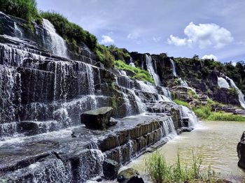 Scenic view of waterfall against sky