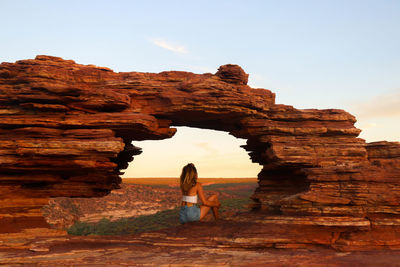 Sunset back of woman at natural red rock window with views in kalbarri national park in australia