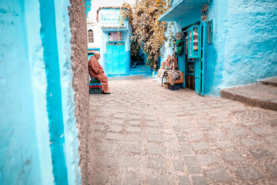 Rear view of man walking on street amidst buildings