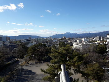 Trees and cityscape against sky