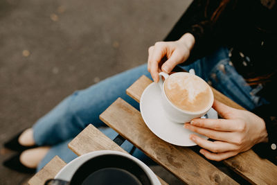 High angle view of woman holding coffee cup on table