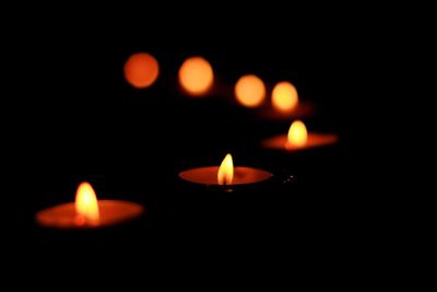 Close-up of lit candle against black background