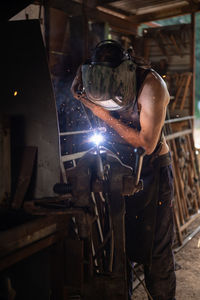 Front view of blacksmith welding a piece of iron in his home workshop. blacksmith concept.