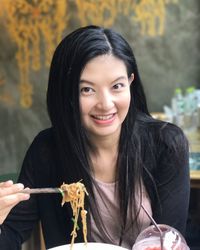 Portrait of a smiling young woman holding camera