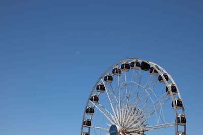 Low angle view of ferris wheel against clear blue sky