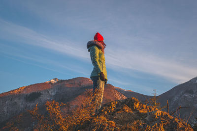 Rear view of woman standing on mountain against sky