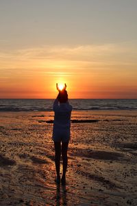 Rear view of women standing on beach during sunset