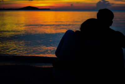 Silhouette couple against sea during sunset