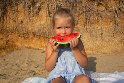 Portrait of cute girl eating food at beach