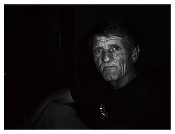 Close-up portrait of man making face against black background